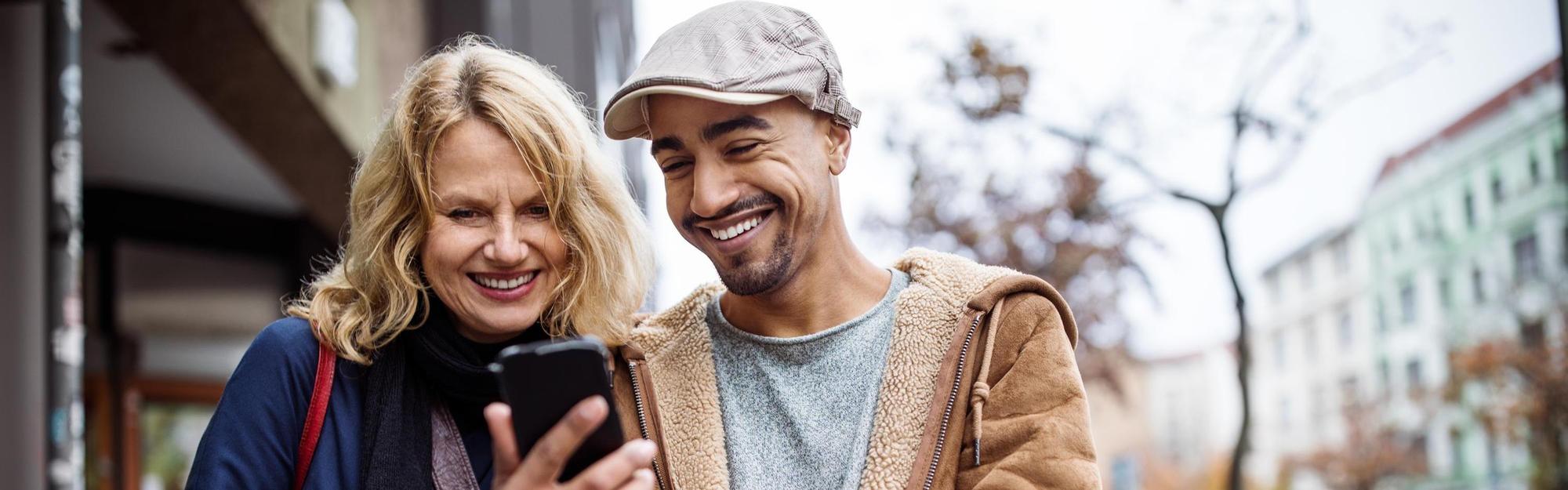 Happy man showing mobile phone to friend