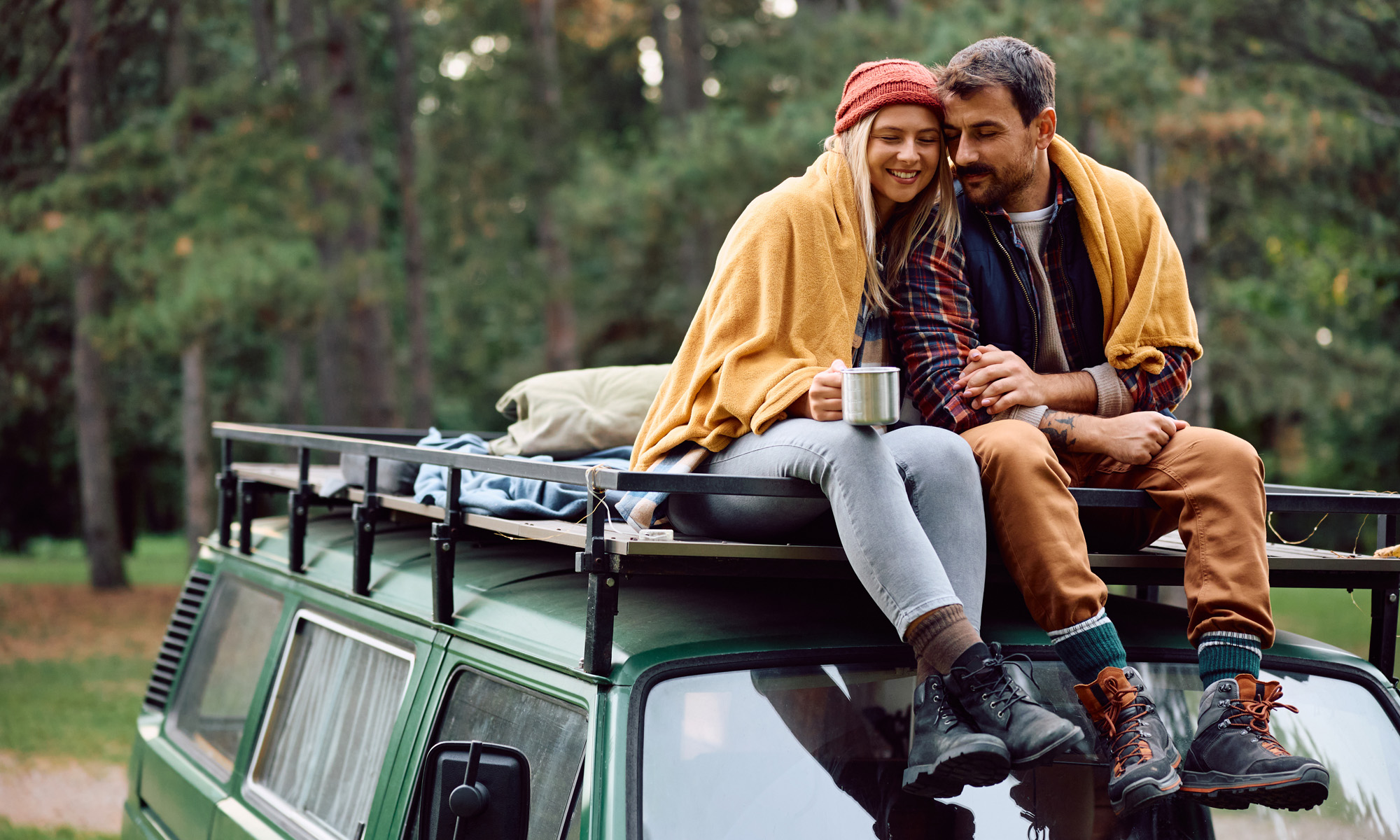 En kvinna och en man sitter på taket på en campingvan