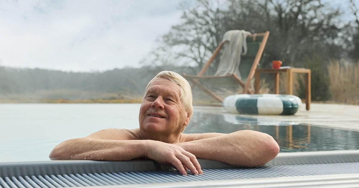 En nöjd senior som njuter av att bada i sin pool