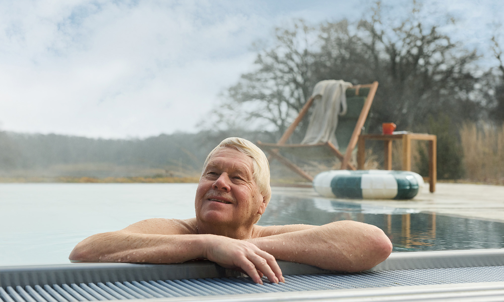 En nöjd senior som njuter av att bada i sin pool