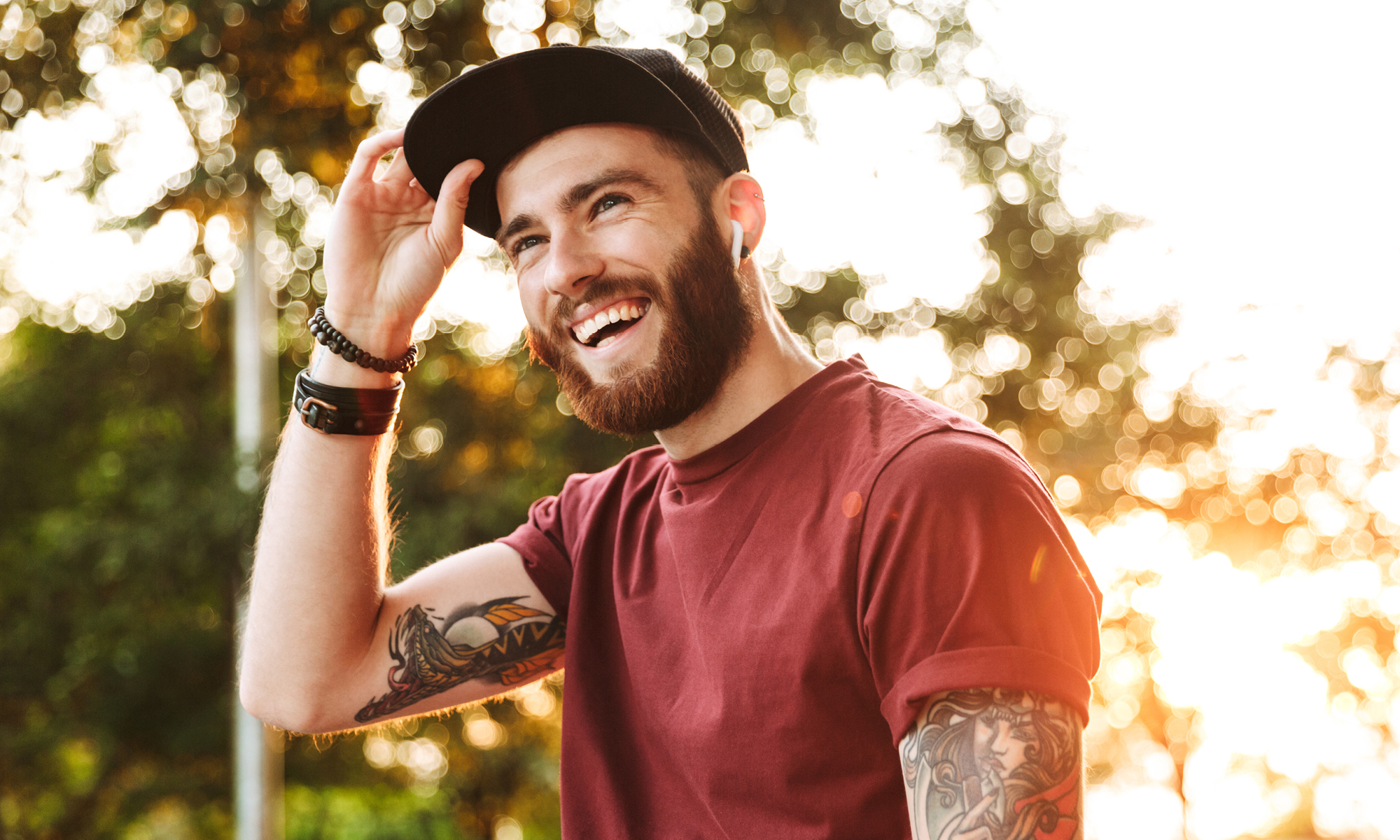 Ung glad man med tatuerade armar och airpods i öronen